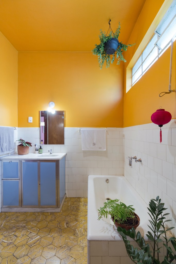 banheiro com meia parede pintada de amarelo
