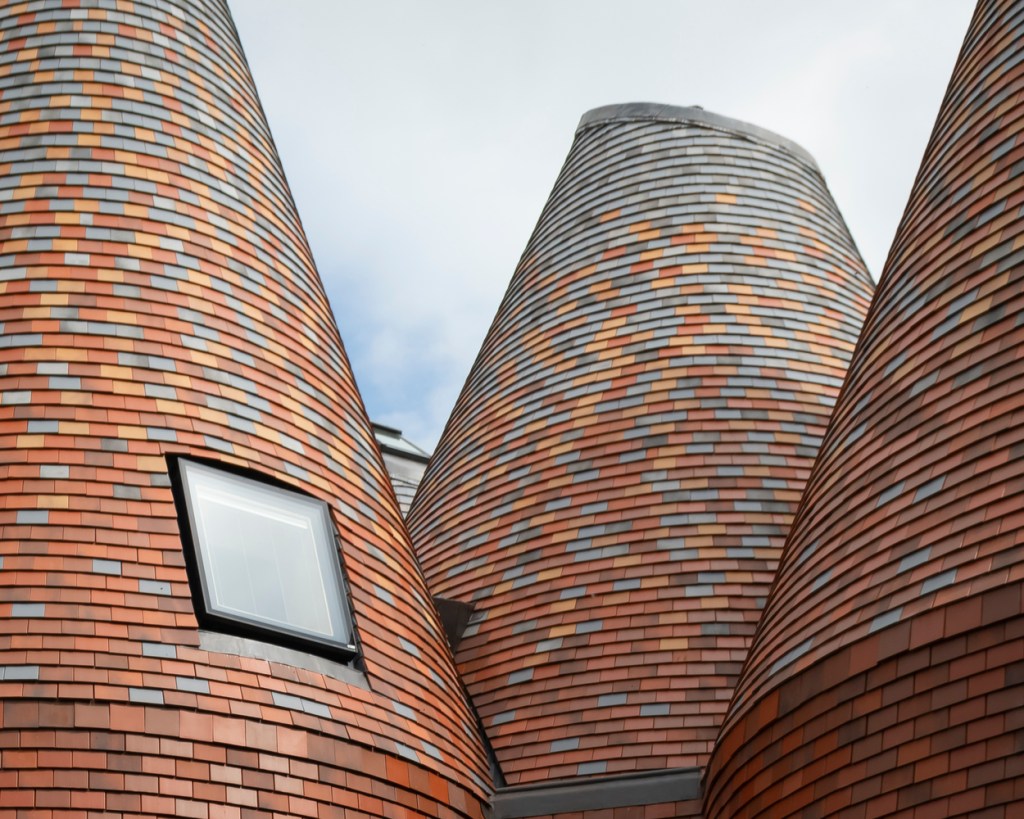 Telhado de três das estruturas formados por peças retangulares de cerâmica, com janela à vista 