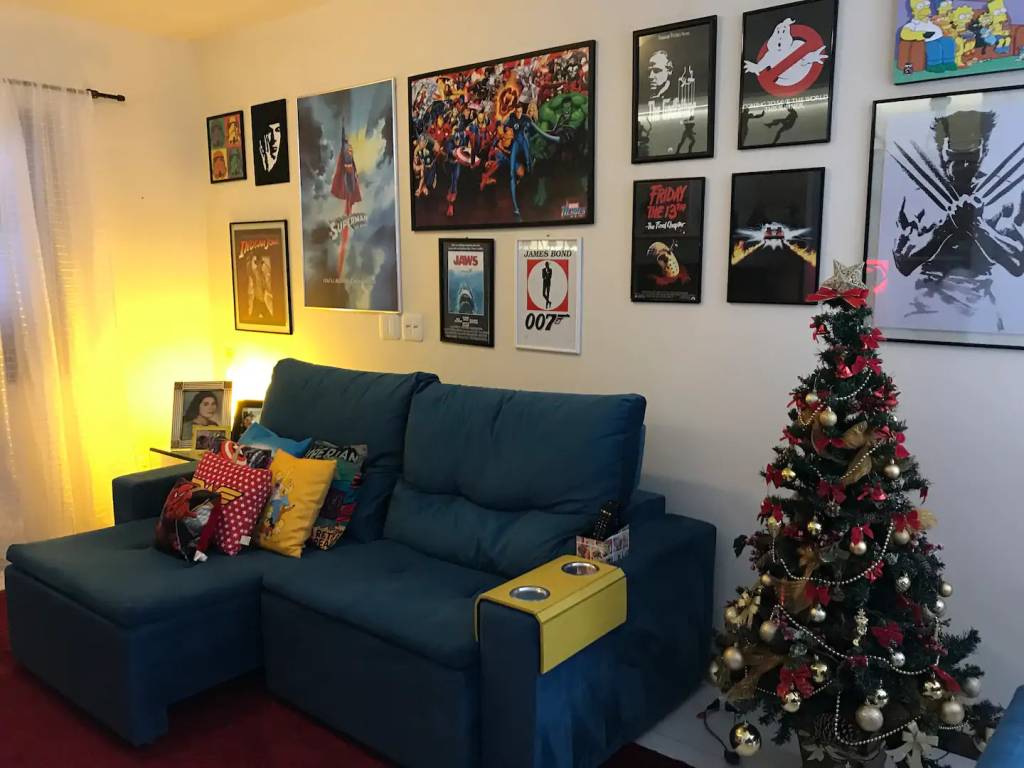 Sala com sofá azul com parede decorada com quadros temáticos de super heróis em tamanho diferentes