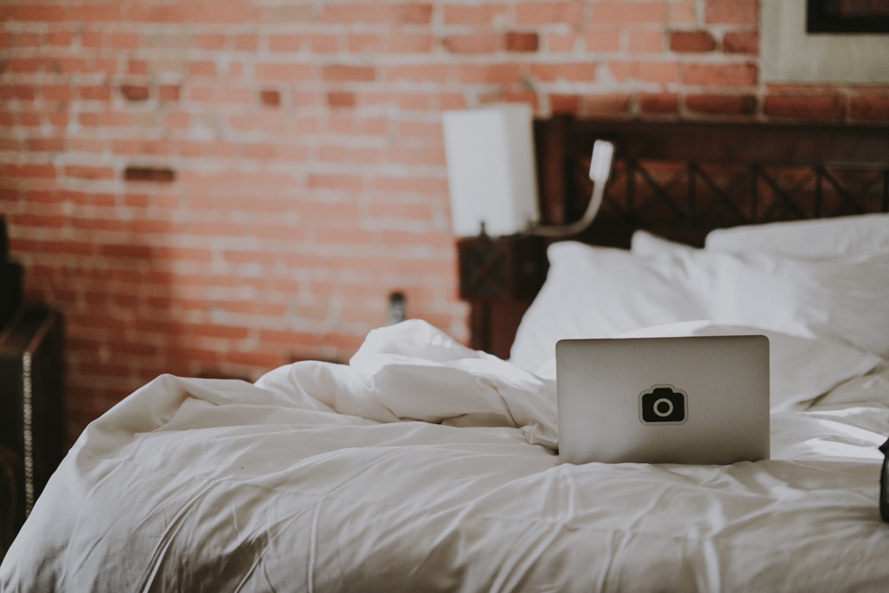 Quarto com parede de tijolinhos e roupa de cama branca