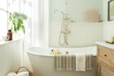 Banheiro com banheira em cores claras e piso de madeira