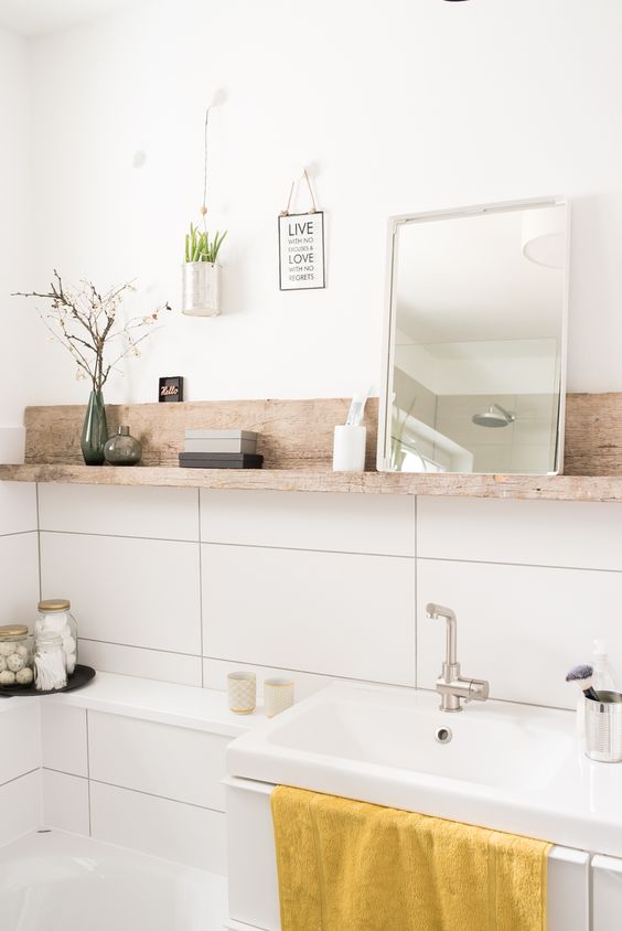 13-dicas-para-decorar-banheiros-pequenos-casa.com-12 Banheiro com uma prateleira esguia de madeira acima da pia, com um espelho, planta e produtos de banheiro