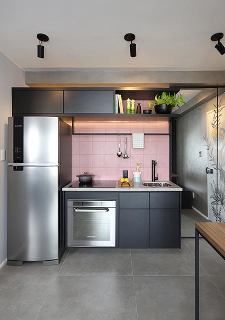 Cozinha com chão de cimento queimado, armários pretos e ladrilhos rosa