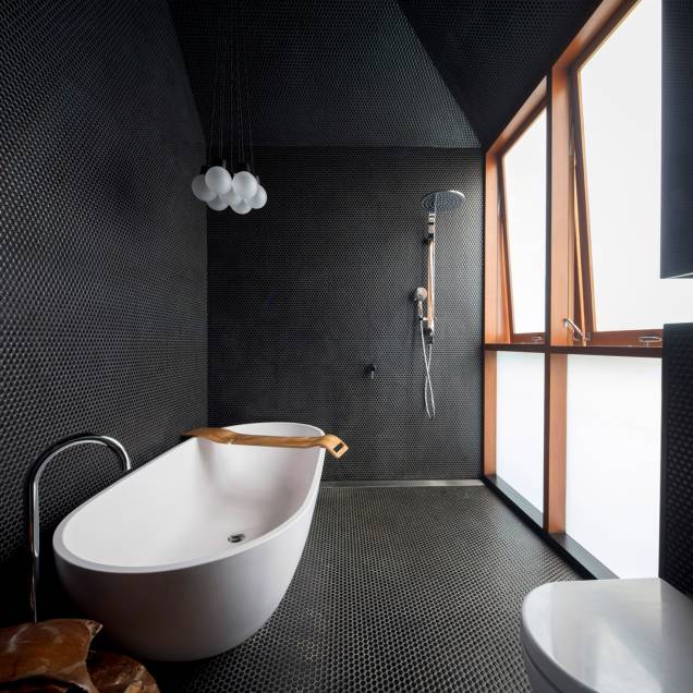 Screen House, Sydney, Austrália, por Carter Williamson Architects | O banheiro do Screen House, do estúdio de arquitetura Carter Williamson, é coberto do chão ao teto com azulejos pretos táteis para criar um ambiente de spa para seus proprietários.Uma banheira independente foi colocada sob uma luz pendente em forma de bolha que está suspensa no telhado inclinado assimétrico Screen House, Sydney, Austrália, por Carter Williamson Architects | O banheiro do Screen House, do estúdio de arquitetura Carter Williamson, é coberto do chão ao teto com azulejos pretos táteis para criar um ambiente de spa para seus proprietários.Uma banheira independente foi colocada sob uma luz pendente em forma de bolha que está suspensa no telhado inclinado assimétrico