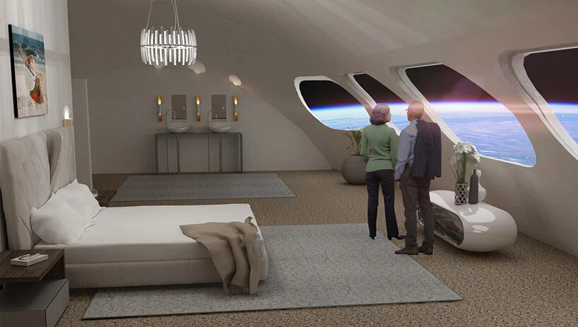 em-2027-teremos-um-hotel-no-espaco-casa.com-2 Quarto na cor bege com um cama e duas pessoas olhando pela janelas que dá vista para o espaço e para a Terra