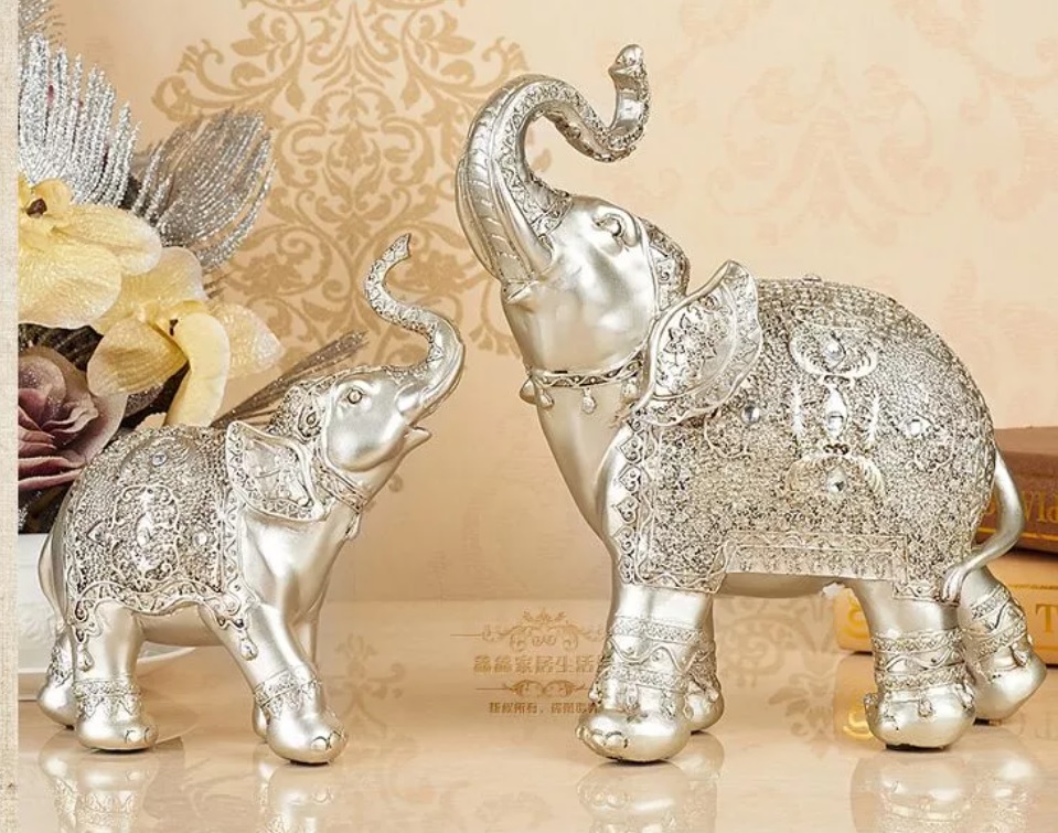 objetos-negatividade-elefante-09 Dois elefantes prateados pequenos com as trombas levantadas, um de frente para o outro