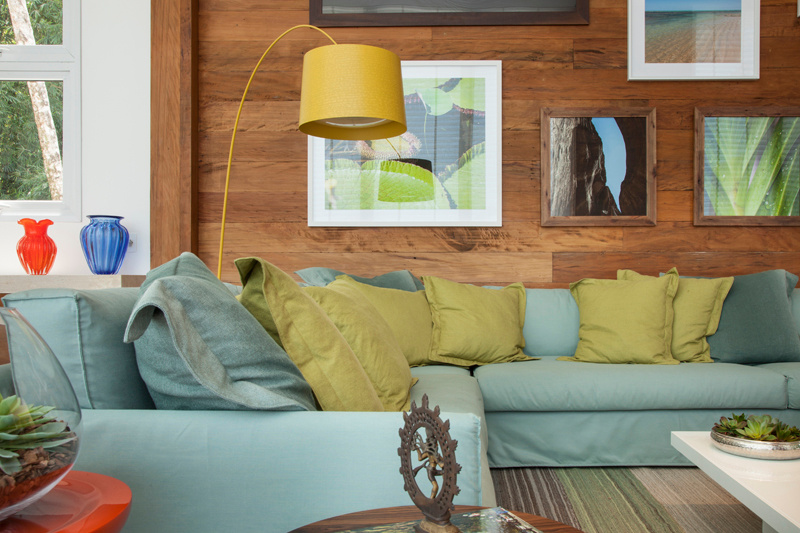 Cores; paleta de cores; chakra; sala de estar; sofá azul; luminária de piso; luminária amarela; parede de madeira; gallery wall