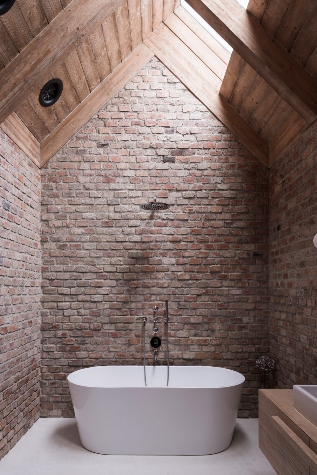 Banheiro com banheira solta e paredes em tijolinho