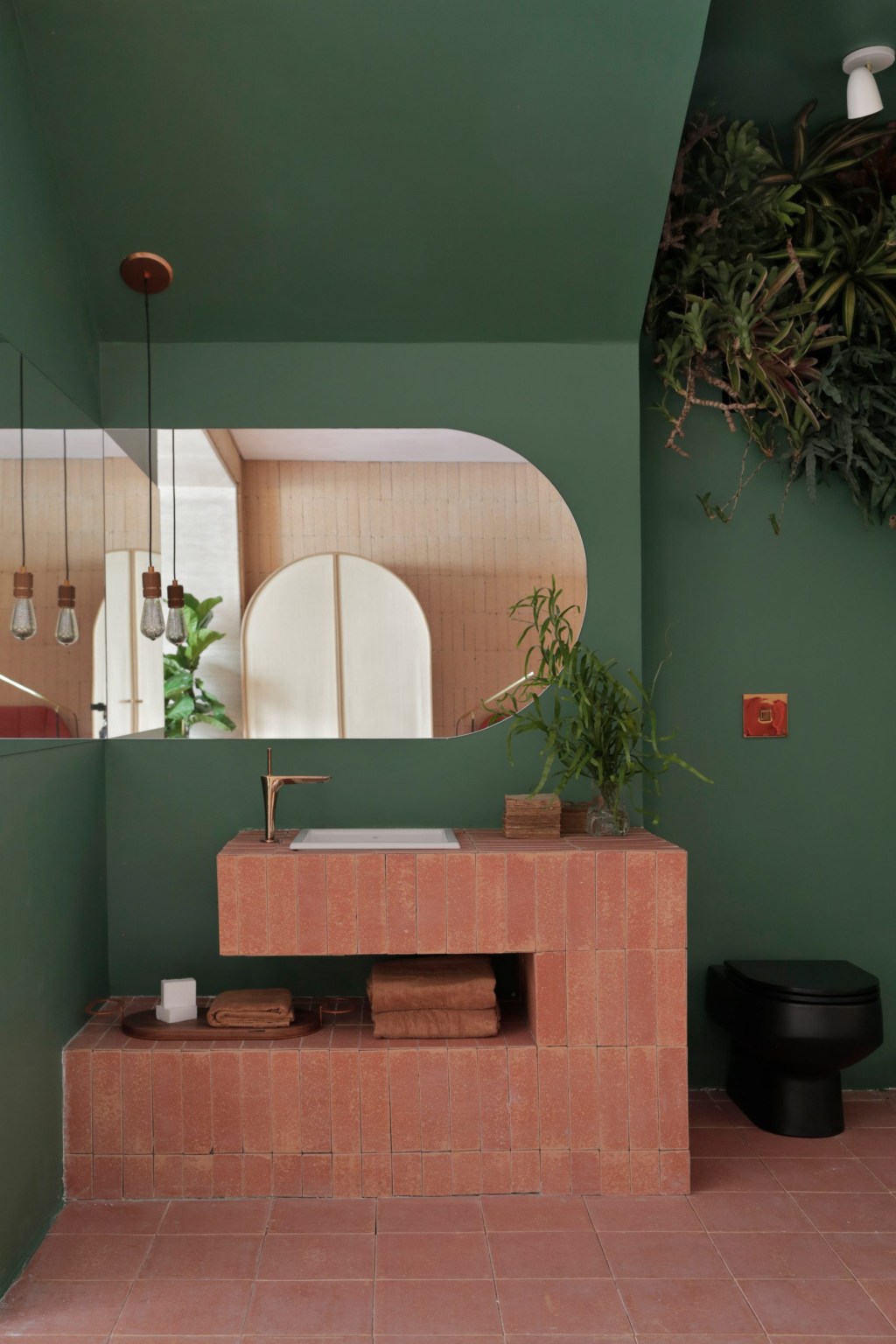 Banheiro com paredes verdes e bancada em tijolinhos