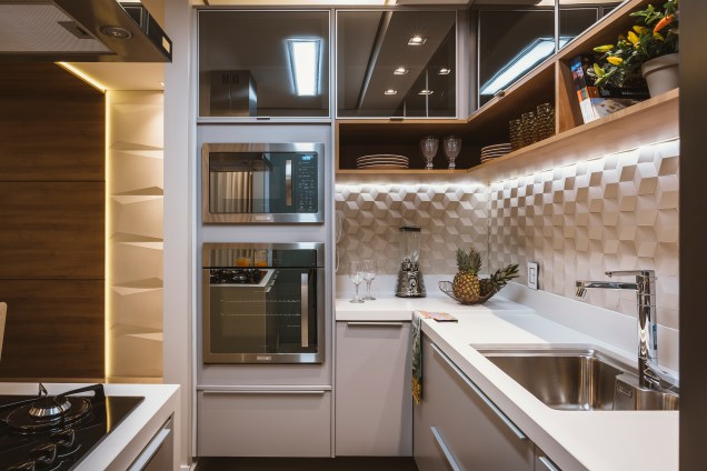 Na cozinha, os nichos abaixo dos armários aéreos possibilitam a exposição de pratos, copos e taças, além de livros de receitas e plantinhas