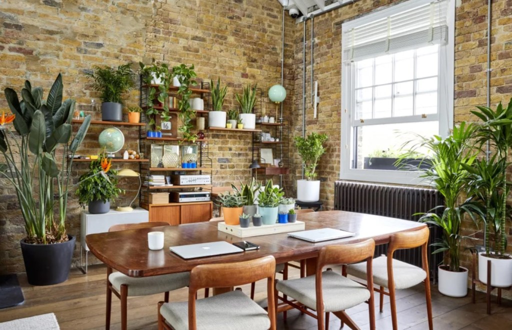 Urban jungle; sala com parede de tijolinhos; mesa de madeira; estante com plantas; plantas