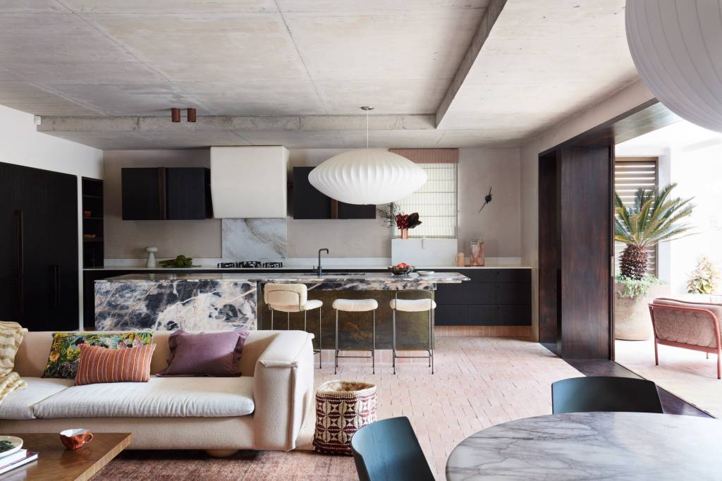 Sala de estar integrada com cozinha, em tons claros, que se conecta ao jardim
