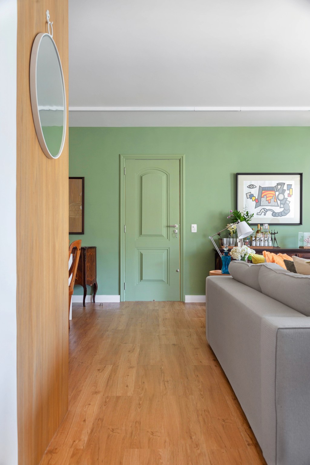 Sala de estar com parede verde claro e piso de madeira