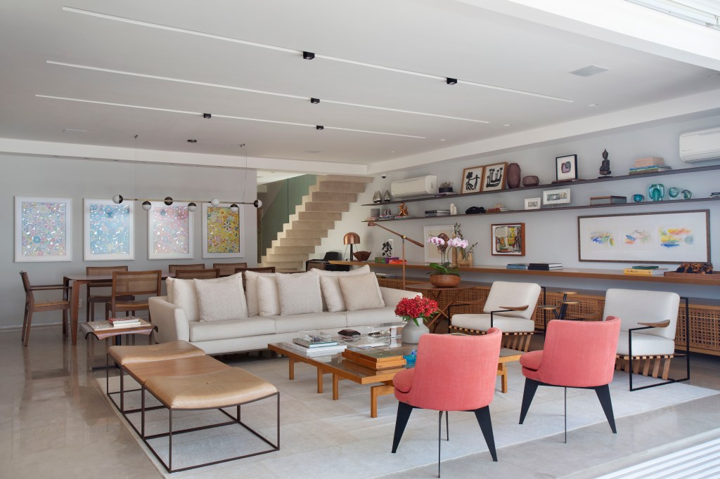 Sala de estar ampla com varanda integrada, sofá branco, poltronas vermelhas, mesa de centro 