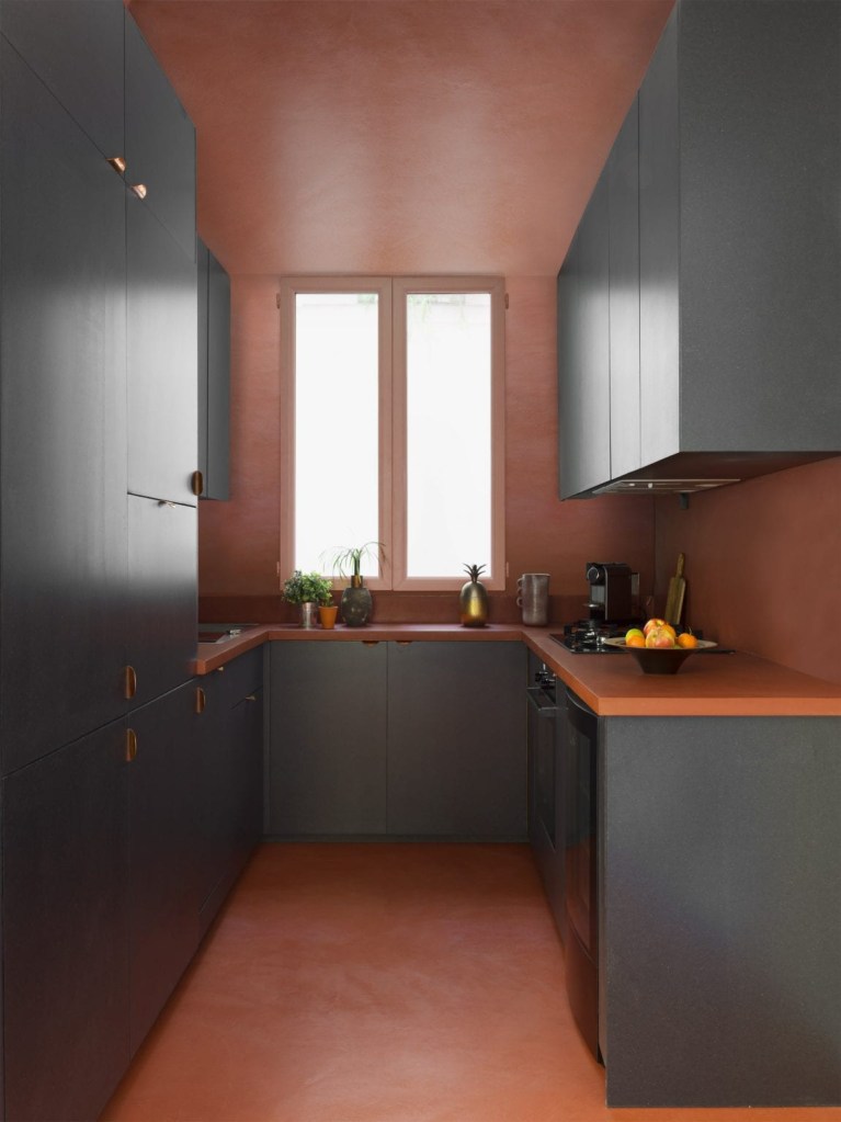 Cozinha em formato de u com marcenaria cinza escura e paredes salmão