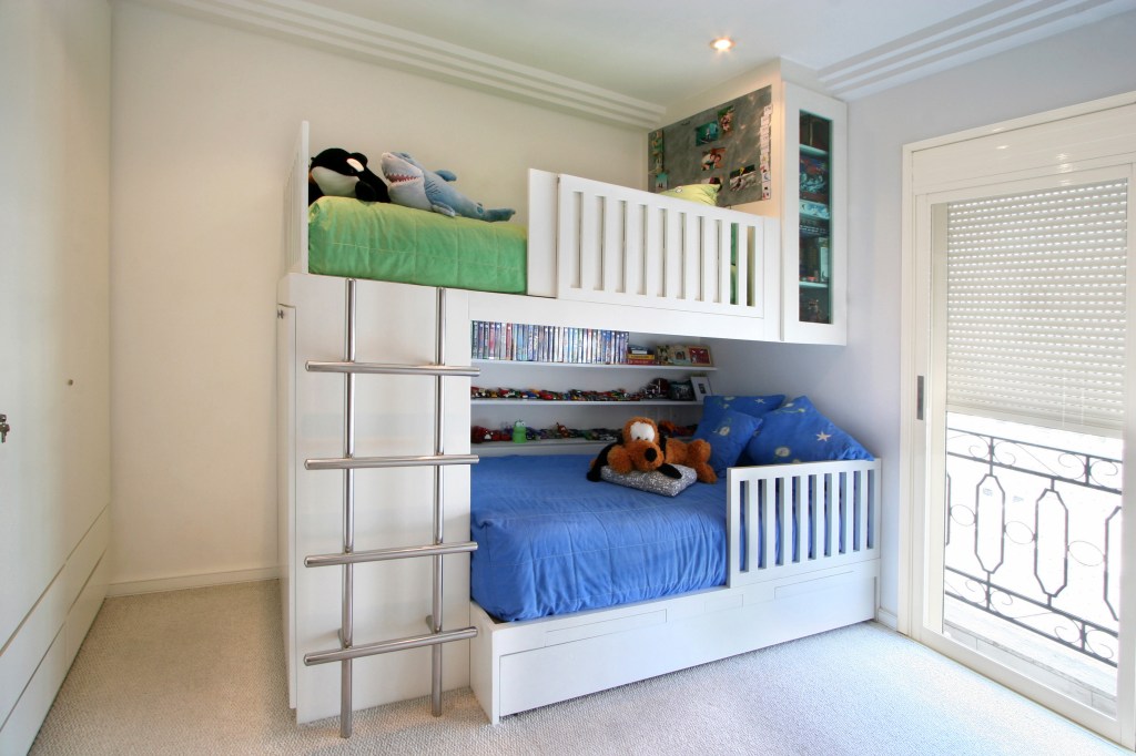 casa-segura-para-criancas-casa.com-karina-korn-nicola-labate Quarto com beliche branca, com escada do lado esquerdo. A cama de baixo tem roupa azul, enquanto a de cima tem roupa verde