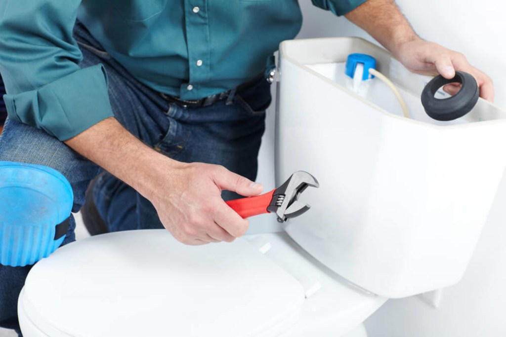Homem com ferramenta na mão consertando vaso sanitário