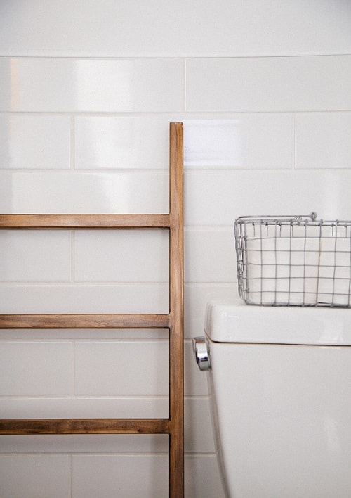 Caixa de vaso sanitário em banheiro ao lado de escada com cesta de arame em cima