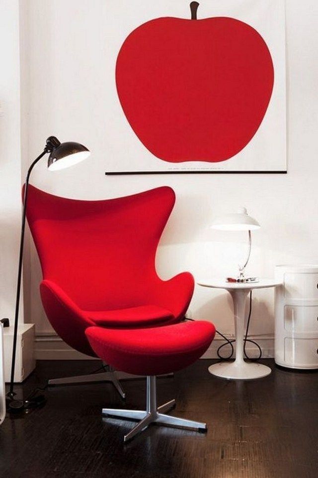 genz-millennial-decoração-pinterest-tendencias-04 Cadeira Egg vermelha vibrante. Mesa lateral com abajur, ambos brancos. Piso em madeira, luminária metálica de chão à esquerda. Na parede branca, quadro com maçã no mesmo tom de vermelho da cadeira.