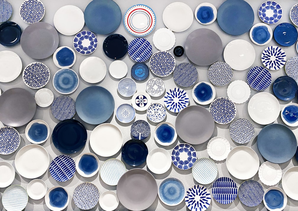 pratos-na-parede-casa.com-8-unsplash-jannet-serhan Composição com diversos pratos azuis e brancos em fundo branco
