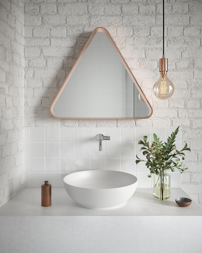 Banheiro minimalista com cuba branca e espelho triangular