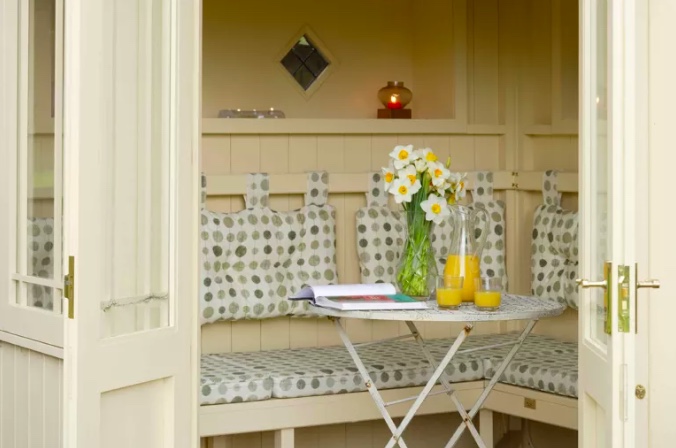 37-cantinhos-de-jardinagem-para-relaxar-e-cuidar-das-plantas-gardeningetc-14 Mesmo que decida por um design menor, você ainda pode fornecer assentos extensos com a escolha certa de peças. Esse banco de canto fino foi construído em torno das bordas da estrutura e maximiza o uso do chão. Uma mesa dobrável de bistrô no centro é uma adição versátil e pode ser guardada quando não estiver em uso. Opte por cores mais claras para aumentar ainda mais a sensação de amplitude e não se esqueça de suavizar o visual com algumas almofadas aconchegantes.