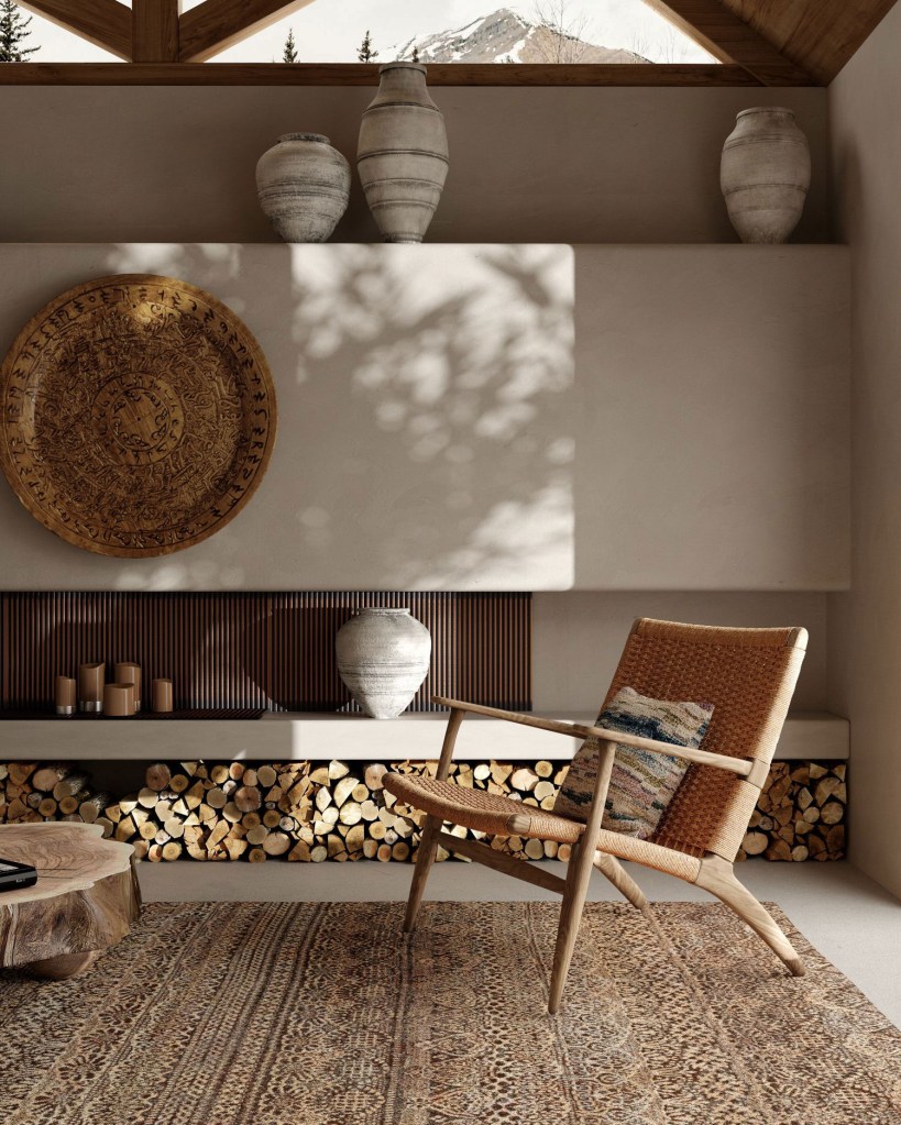 Cadeira e tapete em tons terrosos compões o ambiente, com um compartimento para lenha em parede de cmento queimado com itens de decoração culturais