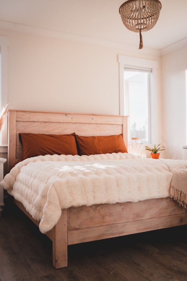 Cama de casal em quarto bem iluminado.