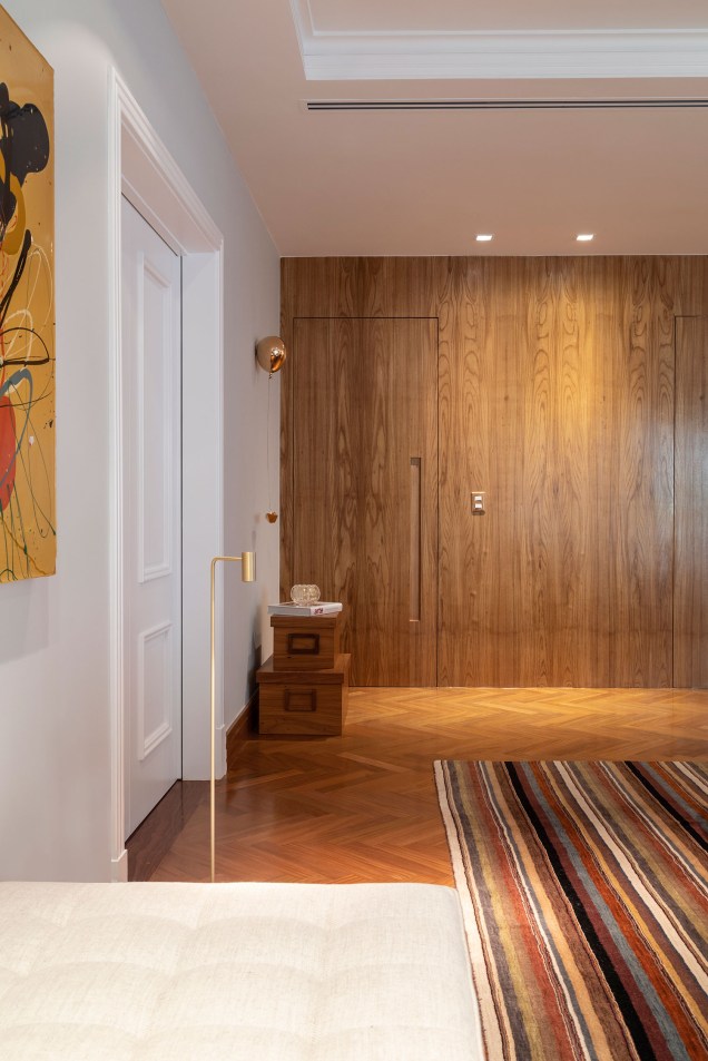 Nesse apartamento realizado por Camila e Thatiana, a porta que leva ao lavabo foi totalmente alinhada ao painel, propiciando a sensação de continuidade