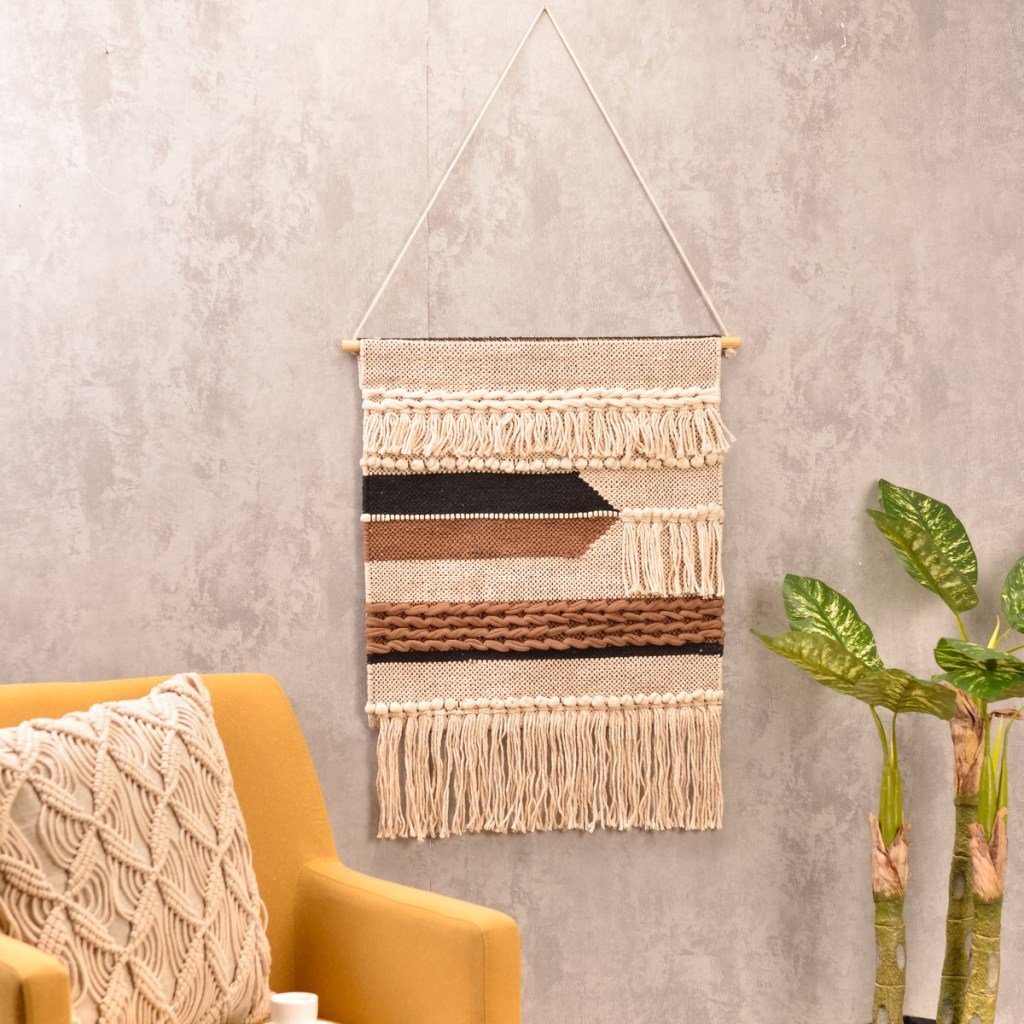 veja-solucoes-para-decorar-as-paredes-da-sua-casa-casa.com-2-etna Parede de cimento queimado, com macramê branco, com detalhes em marrom e bege, uma poltrona amarela com almofada com capa de crochê e planta ao lado