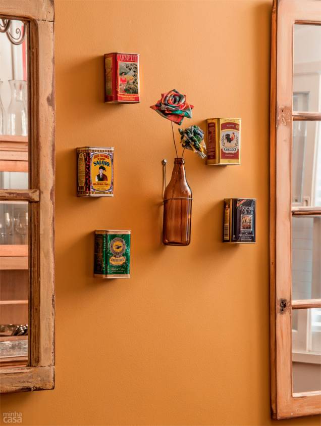 Neste cantinho do restaurante paulistano Sarrasin, o gracioso arranjo fixado na superfície ocre é uma prova de que o casamento entre decoração e sustentabilidade dá certo. Da cozinha, vieram os itens que compõem a ambientação: apoiada em um suporte de parede no centro do conjunto, a garrafa de cerveja sem o rótulo abriga duas delicadas flores de tecido. Ao redor dela, agrupam-se cinco latinhas de azeite vazias, uma de cada cor. Neste cantinho do restaurante paulistano Sarrasin, o gracioso arranjo fixado na superfície ocre é uma prova de que o casamento entre decoração e sustentabilidade dá certo. Da cozinha, vieram os itens que compõem a ambientação: apoiada em um suporte de parede no centro do conjunto, a garrafa de cerveja sem o rótulo abriga duas delicadas flores de tecido. Ao redor dela, agrupam-se cinco latinhas de azeite vazias, uma de cada cor.