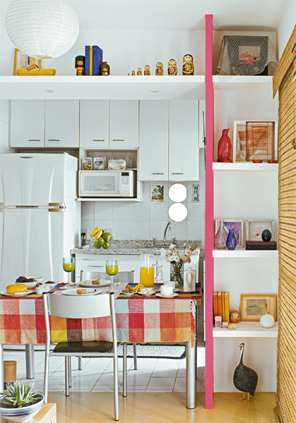 O vão entre a sala e a cozinha veio abaixo e foi emoldurado com prateleiras de gesso no alto e em uma das laterais - nesta, estão apoiados em um painel pintado de rosa-fosco. Dois espelhos redondos foram colados nos azulejos sobre a pia. O vão entre a sala e a cozinha veio abaixo e foi emoldurado com prateleiras de gesso no alto e em uma das laterais - nesta, estão apoiados em um painel pintado de rosa-fosco. Dois espelhos redondos foram colados nos azulejos sobre a pia.