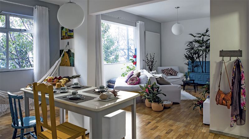 Sala tem parede de tijolinhos e rede de descanso