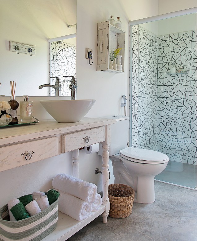 Um estilo de decoração mais afetiva se revela neste banheiro de uma casa de campo em Ibiúna, SP. Assinado pela arquiteta Beatriz Castanho, o projeto exibe elementos rústicos, como o aparador e a prateleira com pintura desgastada, o piso de cimento queimado e os caquinhos de azulejo (Arhus Alto Brilho Branco, de 32 x 57 cm, da Cecafi. C&C, R$ 11,90 o m²).