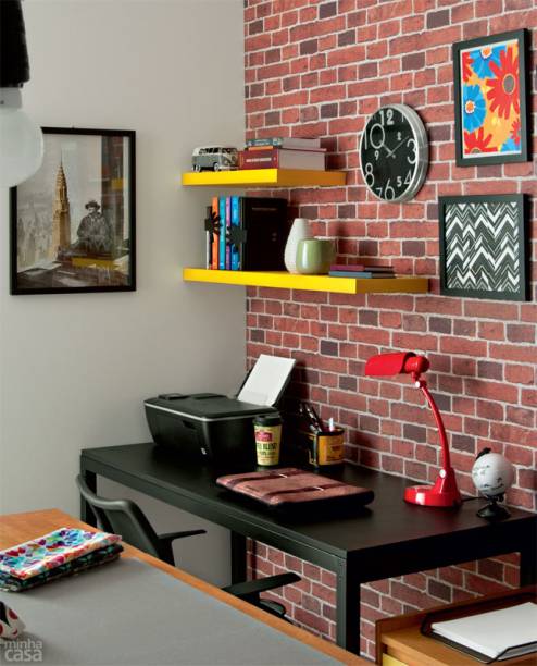O mobiliário é preto, porém a parceria com cores vivas basta para eliminar qualquer sombra de sisudez. O abajur vermelho sobressai, assim como as prateleiras pintadas de amarelo, tons que se repetem em um dos quadros. Nas molduras Toldo, de MDF, vão retalhos dos tecidos Chevron branco e preto e Chita moderna. A composição se completa com o relógio Chic.