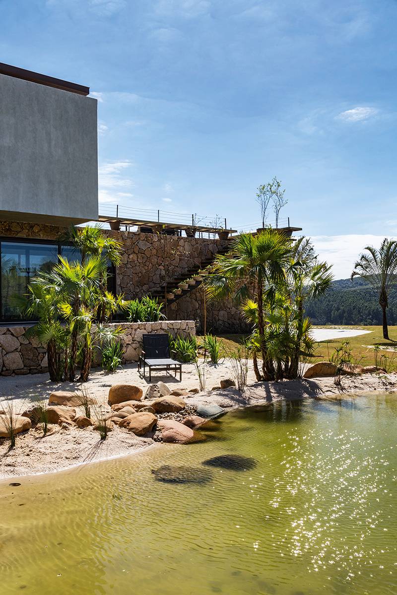 Importante para refrescar, o lago ou piscina natural (feito pela Ecosys, especialista no assunto) ganhou paisagismo no capricho. Palmeiras, papiros e juncos pontuam o reservat&oacute;rioescavado no solo, impermeabilizado e forrado de areia. Acostumados aos peixinhos que mant&eacute;m as &aacute;guas limpas, osfilhos dos propriet&aacute;rios costumam nadar no local. Projeto: Padovani Arquitetos + Associados.