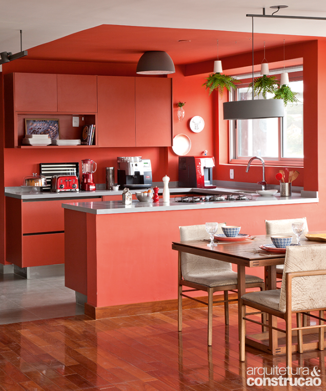 A volumetria desta cozinha foi definida por meio do uso das cores e dos acabamentos. O projeto do escritório pro.a arquitetos privilegiou os armários de laminado no tom goiaba que combinam com o tom apimentado das paredes