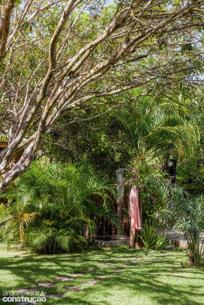 Numa casa de praia, o chuveirão é essencial. E o breve momento sob a água fica ainda melhor com certa privacidade. Por isso, o exemplar deste projeto na Bahia ganhou como localização um ponto discreto – fica apoiado na cerquinha de troncos de eucalipto que fecha parcialmente a área reservada e, do outro lado, tira proveito da barreira visual formada por uma palmeira. O piso soma cimentado com deck de madeira. Ideia do arquiteto Amadeo Romero.