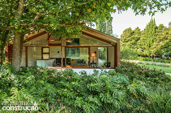 No entorno da cabana no interior de São Paulo, massas de espécies com formas, cores e texturas variadas embelezam a área externa. Sucedem-se maciços com exemplares de costela-de-adão (a vegetação com folhagem grande, em primeiro plano, adequada a locais de meia-sombra) e ixora – o arbusto com flores cor-de-rosa, à dir. O paisagismo é de Isabel Duprat.