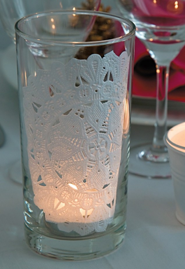Um copo de requeijão decorado com um papel rendado se transforma em uma lamparina cara. A vela foi colocada, antes, em um copo menor, com o objetivo de evitar acidentes.