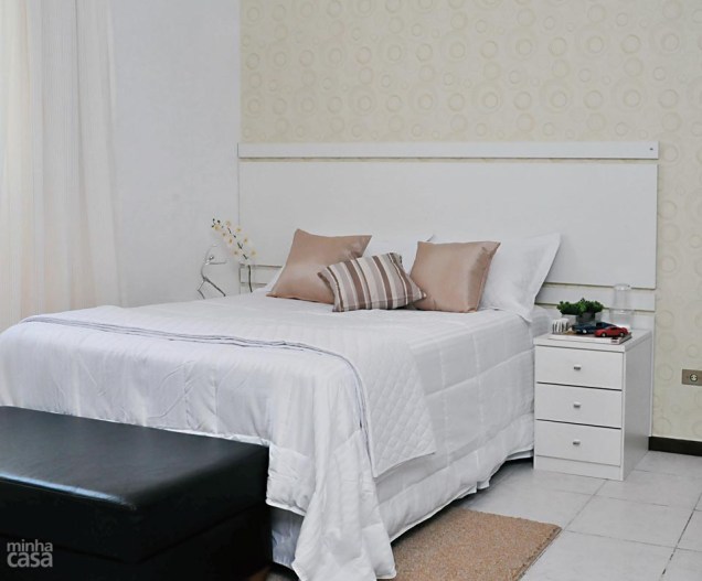 O papel de parede deste quarto projetado por Renata Cáfaro soma estampa e brilho discretos e as cores harmonizam com o enxoval da cama. A cabeceira é de MDF revestido de laminado melamínico branco e complementa a base de cama box.