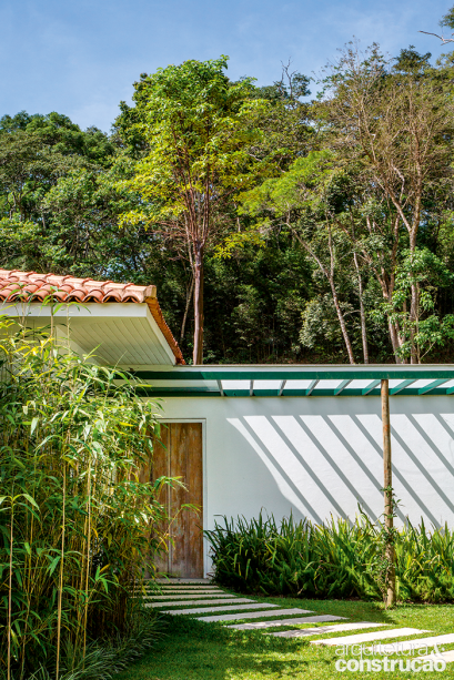 Um beiral generoso (1 m), cerca toda a fachada, resguardando as aberturas de sol e chuva. Apenas sobre a porta de entrada, algo difere: o pergolado de alumínio verde com vidro, feito sob medida para enroscar a trepadeira flor-de-são-miguel.