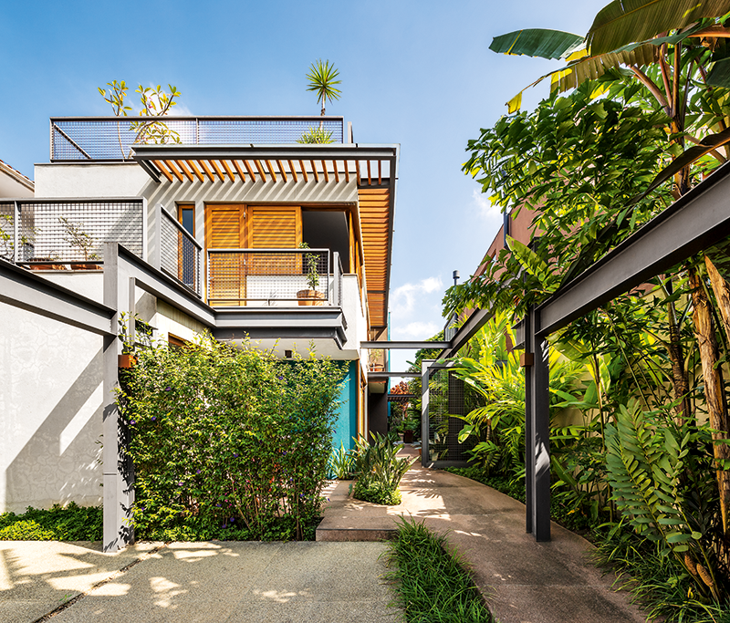 Casa com grandes aberturas é cercada por jardins