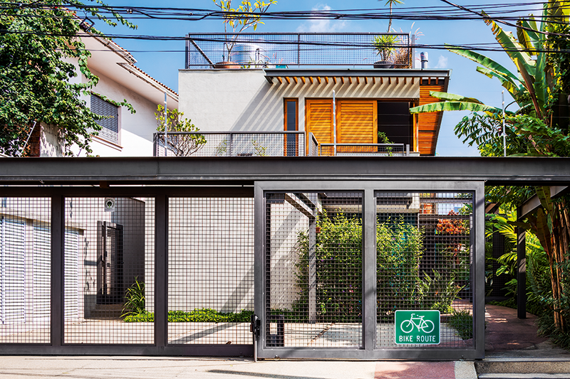 Casa com grandes aberturas é cercada por jardins