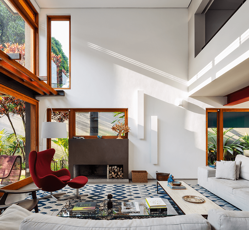 Casa com grandes aberturas é cercada por jardins