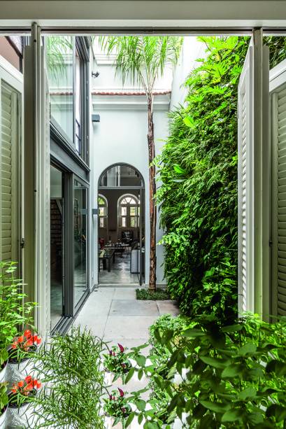 No pátio interno, o jardim vertical (Jardim Imaginário e Duda Abud Paisagismo) de 4,80 m de altura forra o muro com samambaias, orquídeas e bromélias. A palmeira jerivá reverencia o vizinho Jardim Botânico. Fazendo a ligação com o estar, a esquadria de alumínio com bandeira em arco (Sá Martins), de 1,10 x 3,25 m, pivota e promove ventilação cruzada.