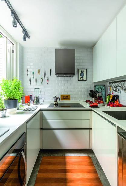 Azulejos retangulares de 10 x 15 cm (linha Metro White, da Roca Cerâmica) cobrem as paredes. Armários da Kitchens e bancadas de Corian (DuPont) complementam o visual todo branco.
