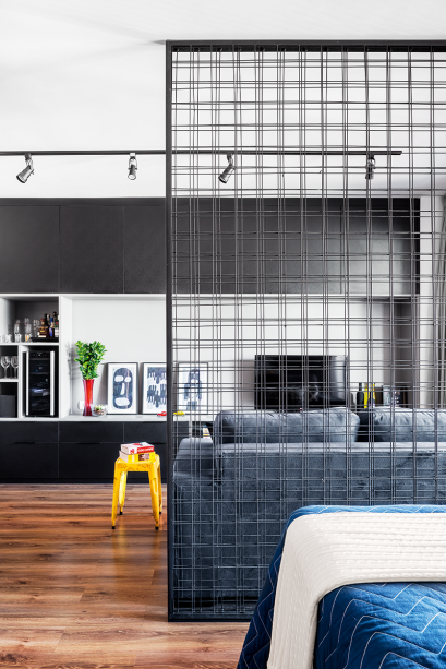 Separar a sala do quarto sem bloquear a passagem de luz é o principal mérito da divisória (2,30 x 2,65 m) idealizada pela arquiteta Marcela Madureira para este apartamento. No trabalho de serralheria, duas telas de aço nervurado – sobrepostas e soldadas – foram fixadas em um perfil U de chapa de ferro dobrada, que faz as vezes de moldura. "Parafusada diretamente no piso e na laje, esta grelha metálica ganhou firmeza”, completa. A pintura com esmalte sintético preto arrematou a proposta. “A releitura de um material bruto, usado na construção civil, se encaixava muito bem no projeto de interiores”, conclui.