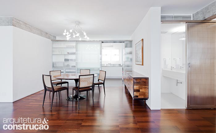 Para a luminosidade da cozinha chegar à copa (e vice-versa), a equipe do AMZ Arquitetos trocou a parede existente por uma estrutura de aço inox com vidro jateado, que inclui duas portas de correr (abertas, elas dão acesso a utensílios e copos).
