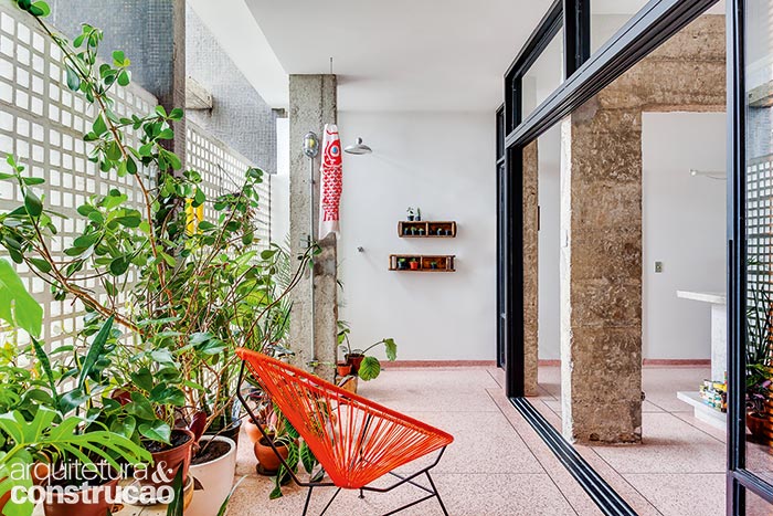 Chuveirão e um jardim em vasos estão presentes nesta espécie de varanda, conquistada pelo escritório SIAA ao trocar as paredes que fechavam toda a extensão de 8,60 m por caixilhos envidraçados. Agora mais visíveis, os elementos vazados da fachada do edifício projetado por Oscar Niemeyer (1907-2012) arejam e iluminam a área social | Histórias de Casa